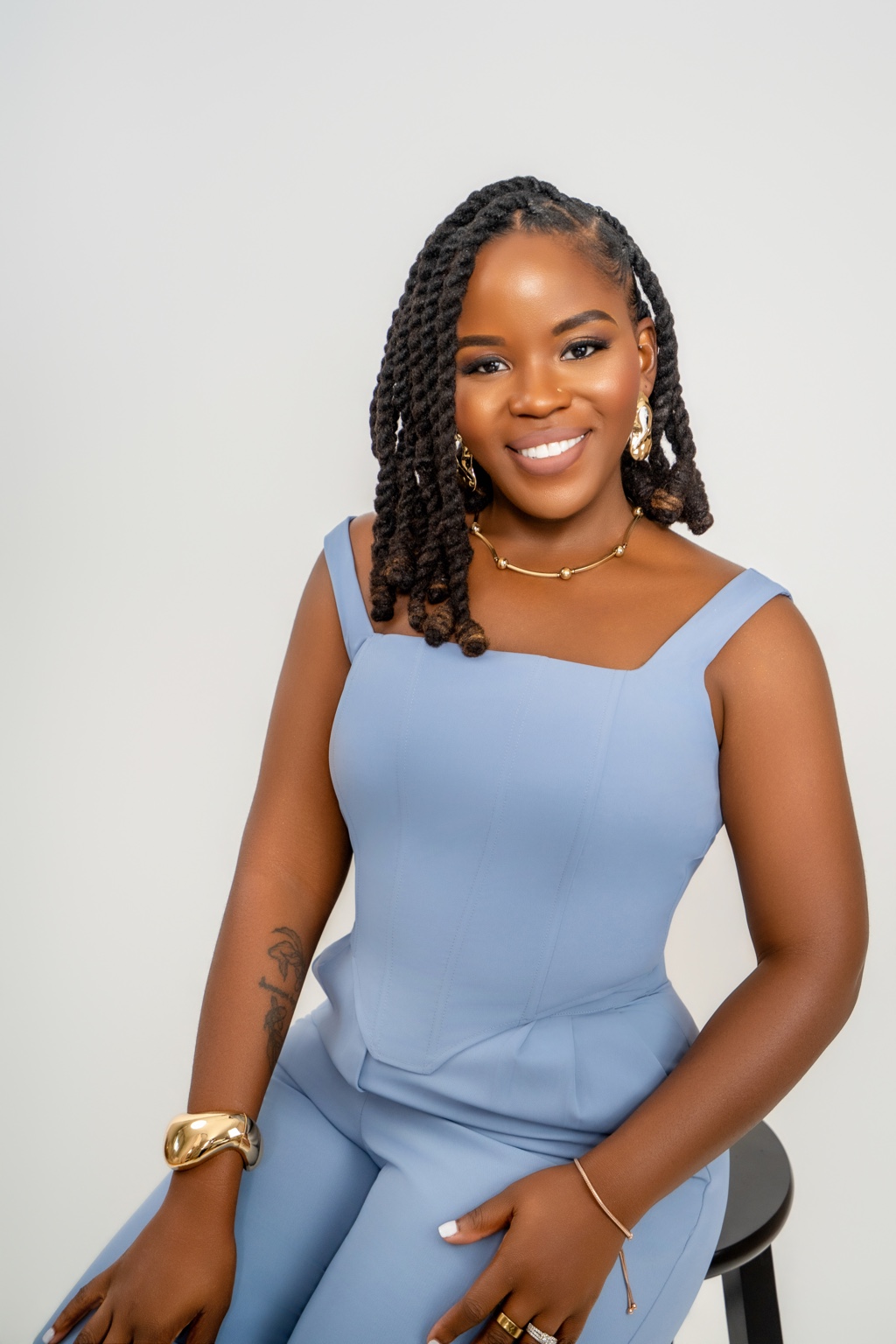 Author Britney Randall seated and smiling in a soft blue suit